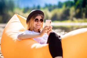 Portrait,Of,Charming,Smiling,Woman,In,Sunglasses,Using,Cellphone,And